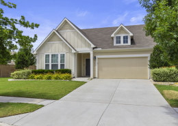 Straight-on view of tan Craftsman home with dormer window accent