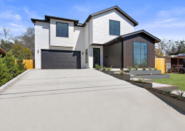 Expansive concrete driveway leading to white and wood two-story Austin home