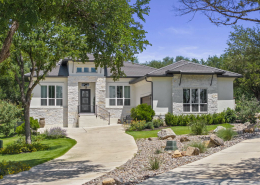 Single-story stone home exterior with xeriscape landscaping and curved driveway