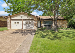 Front exterior of brick home shaded by mature trees