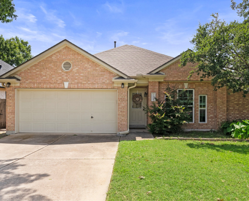 Single-story brick exterior with covered entry, garage, and driveway