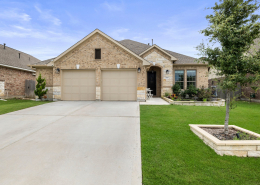 Pflugerville home exterior with three-car garage and stone facade